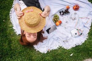 Young woman covers face with a hat while lying on the lawn photo