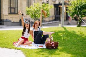 Two women having picnic together, sitting on the plaid photo