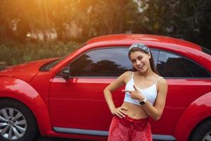 Portrait of pretty Caucasian woman standing against new red car photo