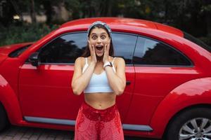 retrato de una mujer bastante caucásica parada contra un auto rojo nuevo foto