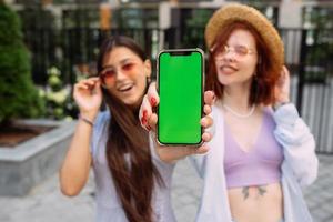 Girlfriends shows their phone to the camera photo
