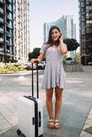 Stylish woman with suitcase looking at camera photo