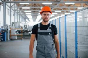 Going forward. Industrial worker indoors in factory. Young technician with orange hard hat photo