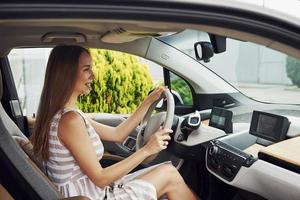 vista lateral. mujer conductora dentro de un automóvil moderno. probando auto nuevo foto