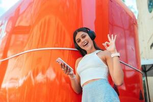 Young woman listening music with wireless headphones in the street photo