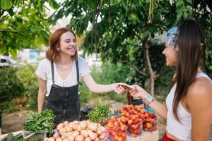 mujer vendedora ofrece verduras frescas y orgánicas en el mercado de agricultores. foto