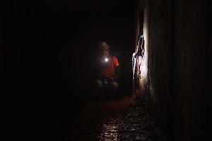 Female digger with flashlight explores the tunnel photo