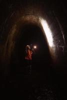 Female digger with flashlight explores the tunnel photo