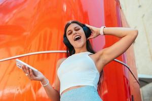 Young woman listening music with wireless headphones in the street photo