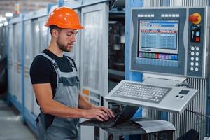 Industrial worker indoors in factory. Young technician with orange hard hat photo