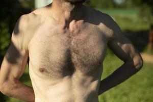 Hairy chest of man on beach. Guy's chest is in sunlight. Body details. photo