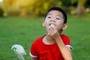 niño asiático comiendo algodón de azúcar con gusto. El algodón de azúcar está hecho de azúcar hilada en tiras finas. como una nube, muchos colores dependiendo del color. enfoque suave y selectivo. foto