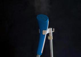 La plancha de vapor azul sobre un fondo negro ahorra tiempo al planchar y conservar la ropa. enfoque suave y selectivo. foto