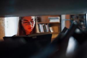 Artificial red light on from the book. Female student is in library that full of books. Conception of education photo