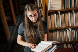 Turning the page. Reading interesting book. Female student is in library. Conception of education photo