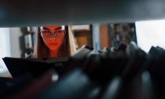 Artificial red light on from the book. Female student is in library that full of books. Conception of education photo