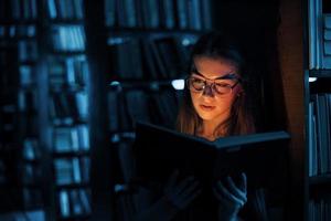 Light from the book in dark room. Imagination conception. Female student is in library that full of books. Conception of education photo