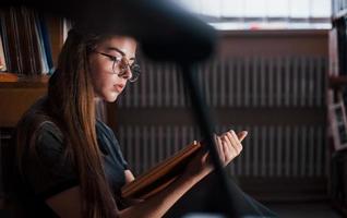 Concentrated at reading. Female student is in library that full of books. Conception of education photo