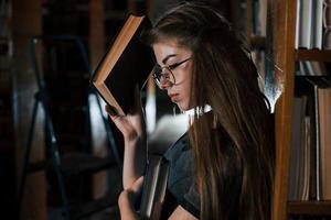 Feels tired. Female student is in library that full of books. Conception of education photo