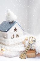 llave de la casa con un llavero en una casa acogedora con decoración navideña. un regalo para año nuevo, navidad. construcción, diseño, proyecto, mudanza a casa nueva, hipoteca, alquiler y compra de bienes raíces foto