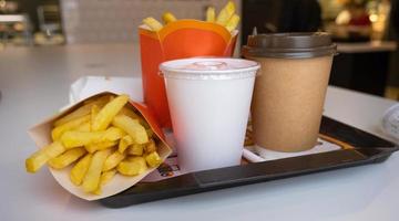 Fast food on a tray in a restaurant. French fries, a glass with a milkshake, coffee photo