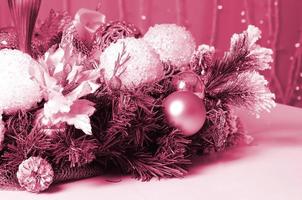 Christmas decorations and toys lie on the surface of a white grand piano. Image toned in Viva Magenta, color of the 2023 year photo