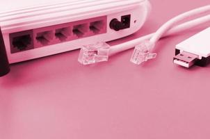 el enrutador de Internet, el adaptador wi-fi usb portátil y los enchufes del cable de Internet se encuentran sobre un fondo naranja brillante. elementos necesarios para la imagen de conexión a Internet en tonos magenta vivo, color del año foto