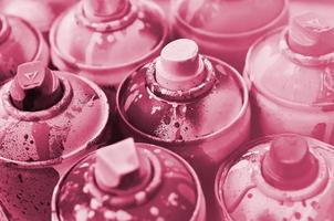 A lot of used spray cans of paint close-up. Dirty and smeared cans for drawing graffiti. The concept of a sweeping and careless drawing of paint. Image toned in Viva Magenta, color of the year photo