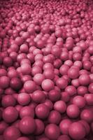 Many plastic balls in a kids ballpit at a playground. Image toned in Viva Magenta, color of the 2023 year photo