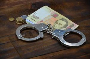 A photograph of a certain amount of Ukrainian money and police handcuffs. Concept of illegal earnings of Ukrainian citizens photo