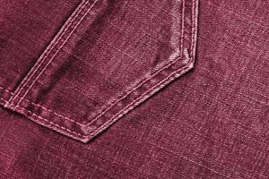 Detailed abstract texture of dark blue denim cloth. Background image of old used denim trousers fabric Image toned in Viva Magenta, color of the 2023 year photo