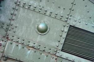 Texture of tank side wall, made of metal and reinforced with a multitude of bolts and rivets photo