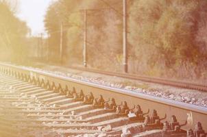 Autumn industrial landscape. Railway receding into the distance among green and yellow autumn trees photo