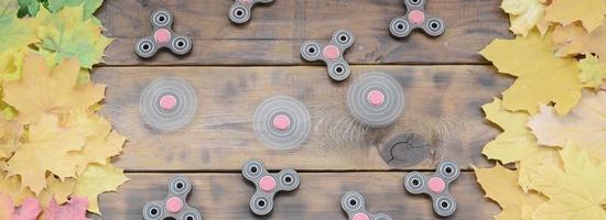 Several spinners among the many yellowing fallen autumn leaves on the background surface of natural wooden boards of dark brown color photo