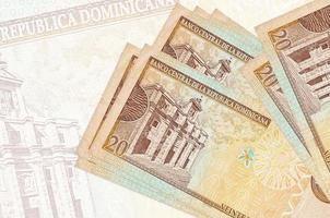 20 Dominican peso bills lies in stack on background of big semi-transparent banknote. Abstract presentation of national currency photo