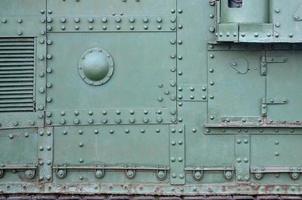 Texture of tank side wall, made of metal and reinforced with a multitude of bolts and rivets photo