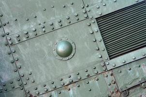 Texture of tank side wall, made of metal and reinforced with a multitude of bolts and rivets photo