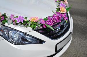 A detailed photo of the hood of the wedding car, decorated with many different flowers. The car is prepared for a wedding ceremony