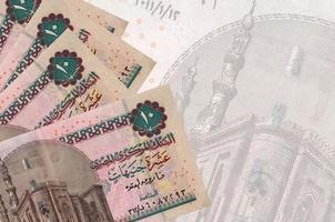 10 Egyptian pounds bills lies in stack on background of big semi-transparent banknote. Abstract business background photo