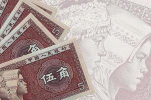 5 Chinese yuan bills lies in stack on background of big semi-transparent banknote. Abstract business background photo