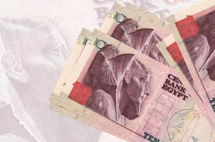 Los billetes de 10 libras egipcias se encuentran apilados en el fondo de un gran billete semitransparente. presentación abstracta de la moneda nacional foto