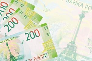 Los billetes de 200 rublos rusos se encuentran apilados en el fondo de un gran billete semitransparente. fondo de negocios abstracto foto