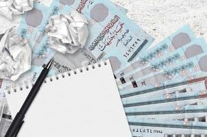 5 Egyptian pounds bills and balls of crumpled paper with blank notepad. Bad ideas or less of inspiration concept. Searching ideas for investment photo