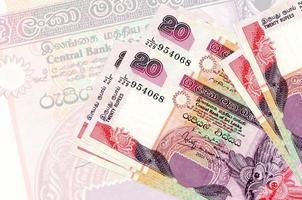 Los billetes de 20 rupias de Sri Lanka se encuentran apilados en el fondo de un gran billete semitransparente. presentación abstracta de la moneda nacional foto