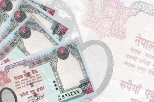 1000 Nepalese rupees bills lies in stack on background of big semi-transparent banknote. Abstract business background photo