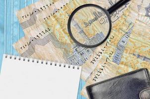 25 Egyptian piastres bills and magnifying glass with black purse and notepad. Concept of counterfeit money. Search for differences in details on money bills to detect fake photo