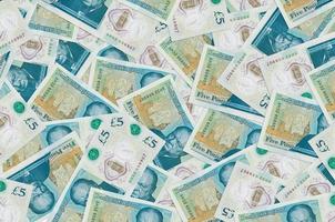 5 British pounds bills lies in big pile. Rich life conceptual background photo