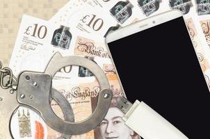 10 British pounds bills and smartphone with police handcuffs. Concept of hackers phishing attacks, illegal scam or malware soft distribution photo