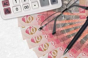 10 billetes de hryvnias ucranianos ventilador y calculadora con gafas y bolígrafo. préstamo comercial o concepto de temporada de pago de impuestos foto