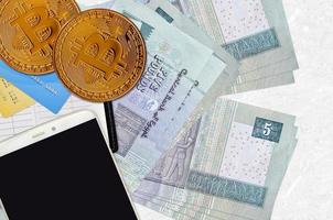 5 Egyptian pounds bills and golden bitcoins with smartphone and credit cards. Cryptocurrency investment concept. Crypto mining or trading photo
